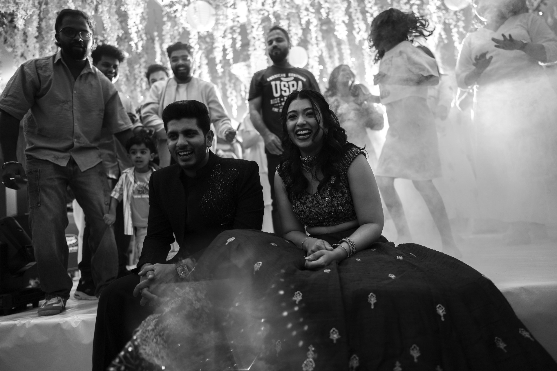 Black-and-white candid of the couple seated together at the reception
